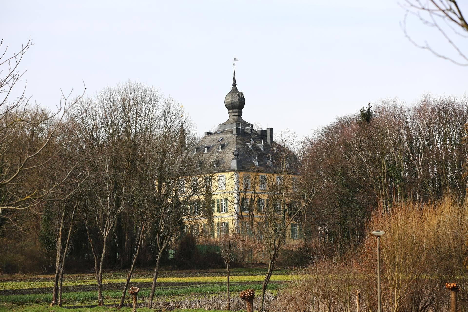 Burg Kendenich in Hürth, barockes Wasserschloss mit Zwiebelturm über den Bäumen