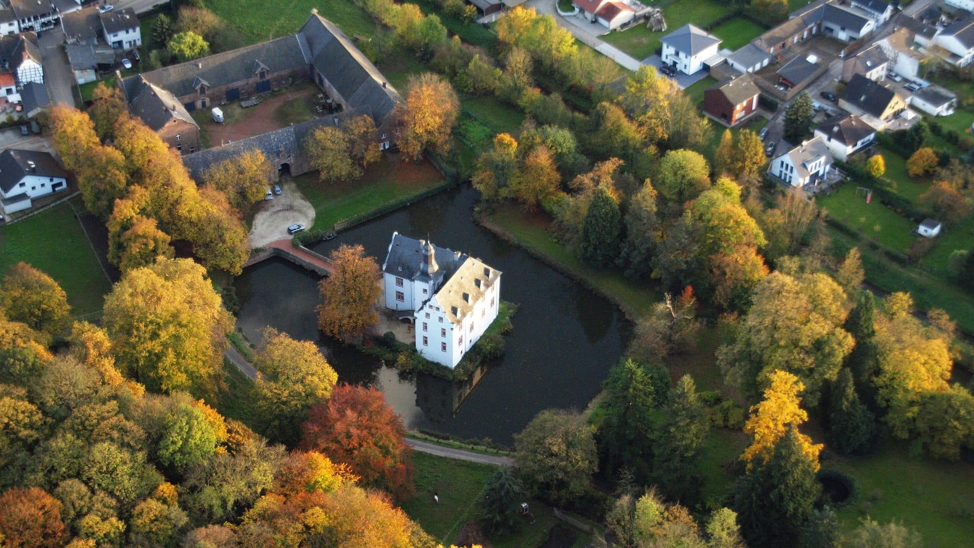 Burg Metternich in Weilerswist, weißes Wasserschloss mit Spiegelung im Wassergraben aus der Luft